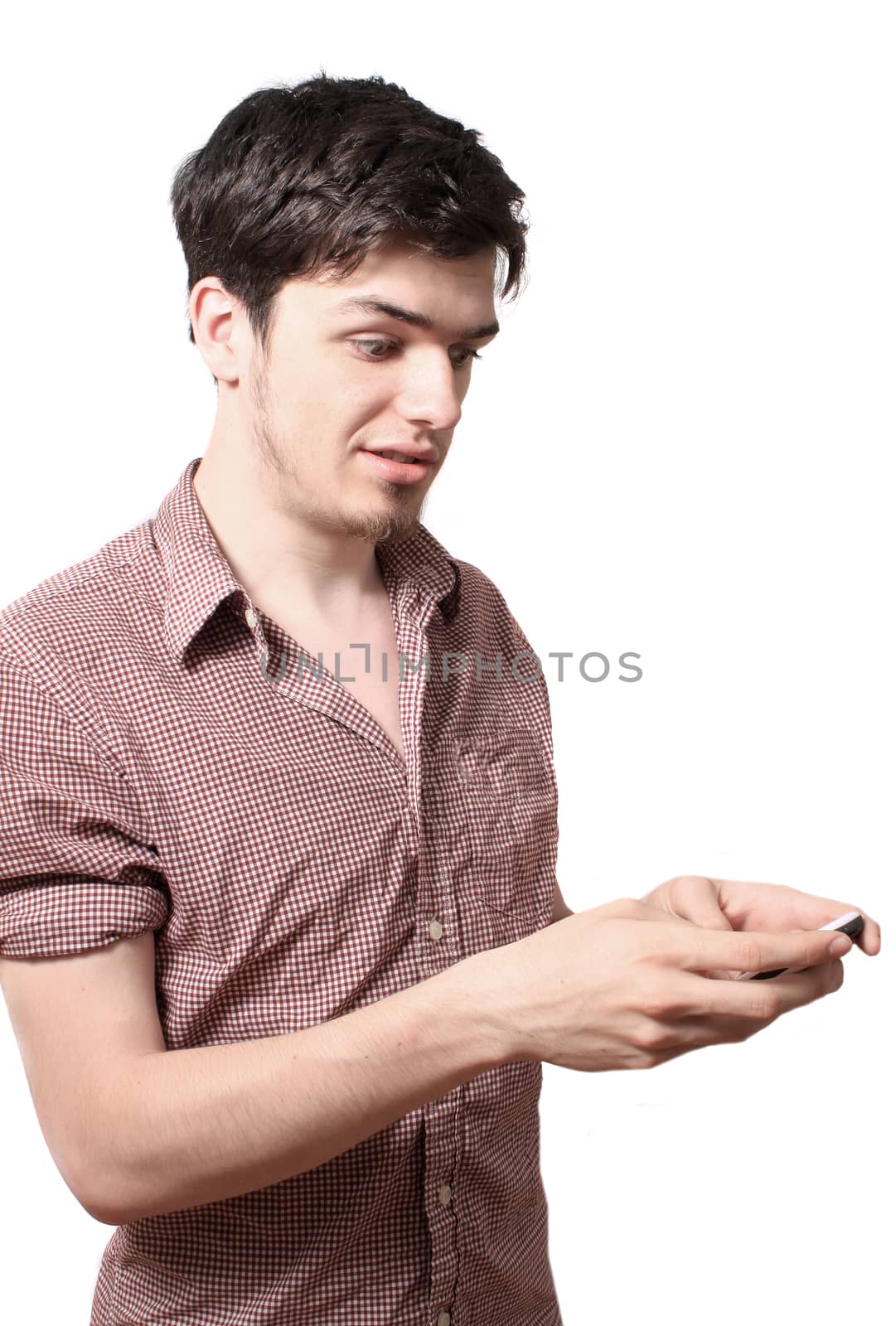 Eighteen year old young man holding his cellphone on a white background with surprised or astonished look on his face