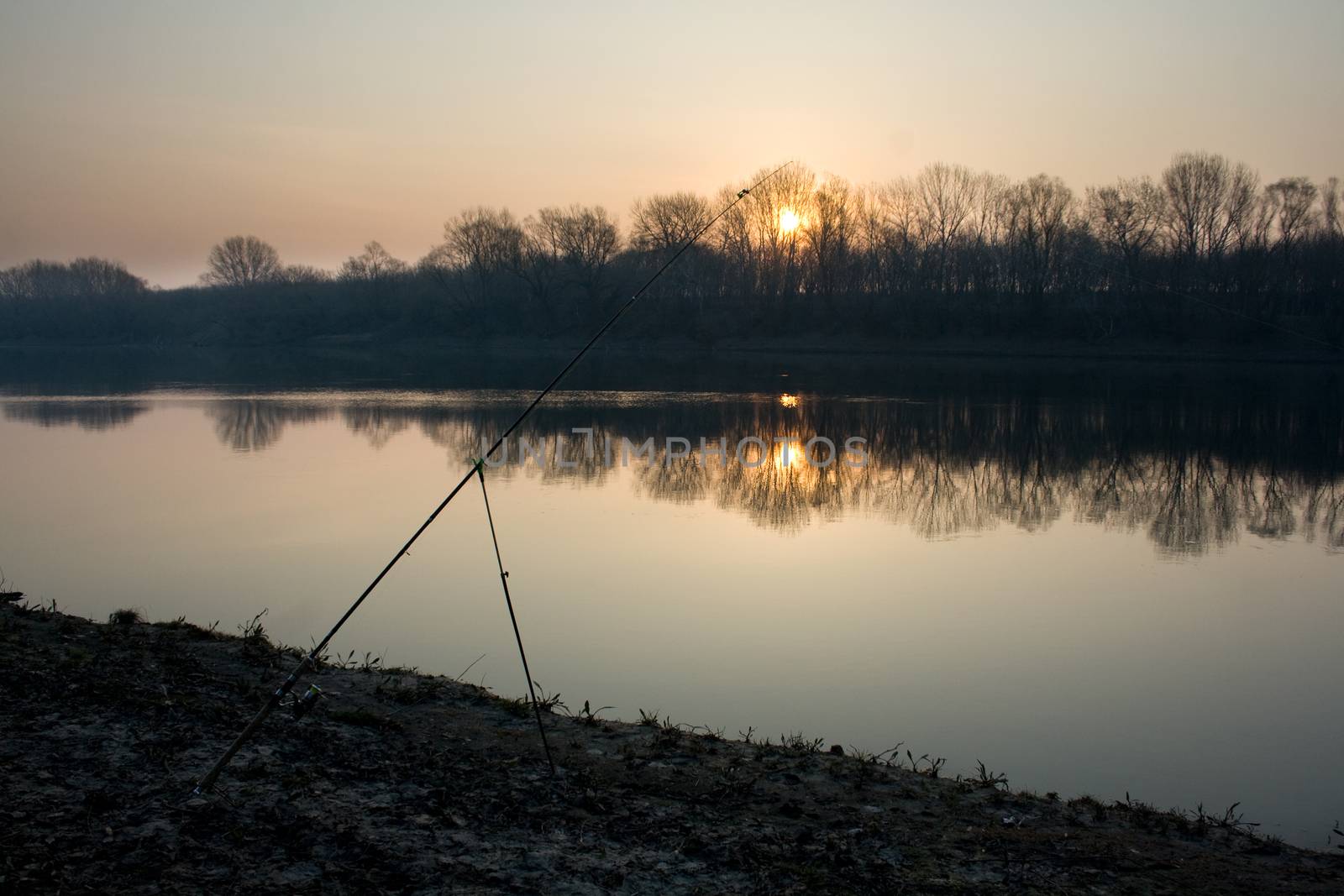 Dawn on the river in early spring. Abandoned fishing rod to catch fish