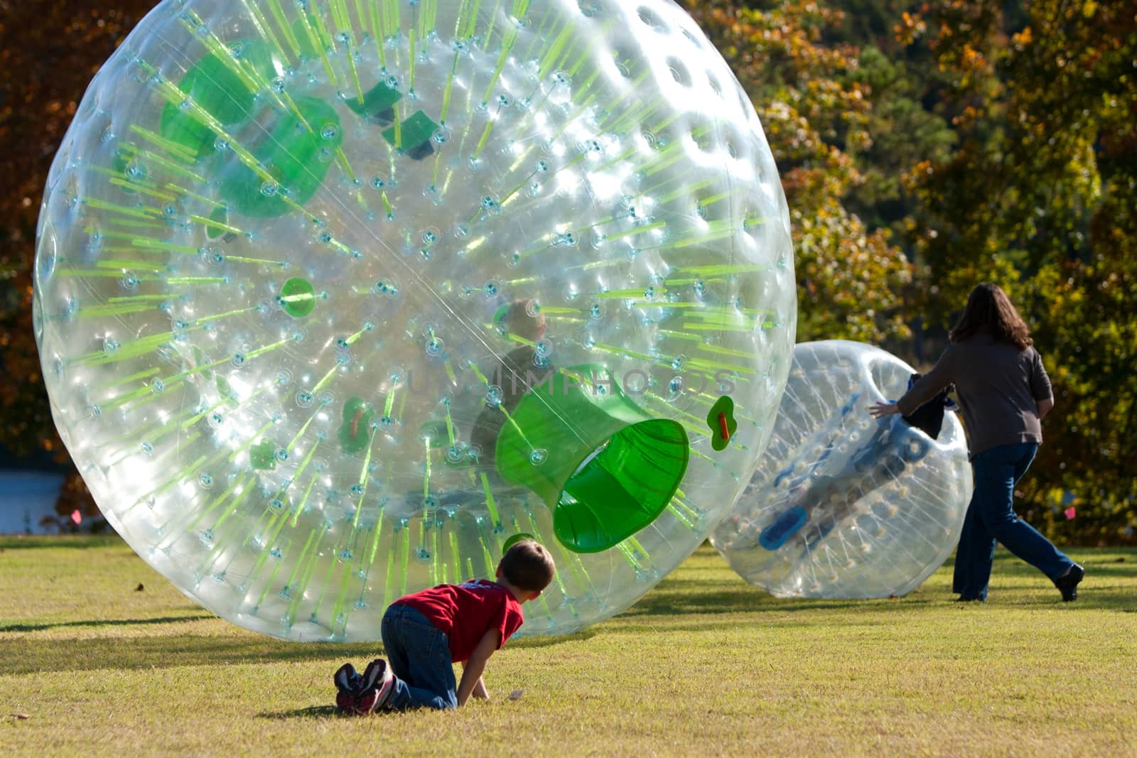Flowery Branch, GA, USA - October 15, 2011:  A mother and child get involved in pushing another child around in a zorb at a fall festival in Flowery Branch. 