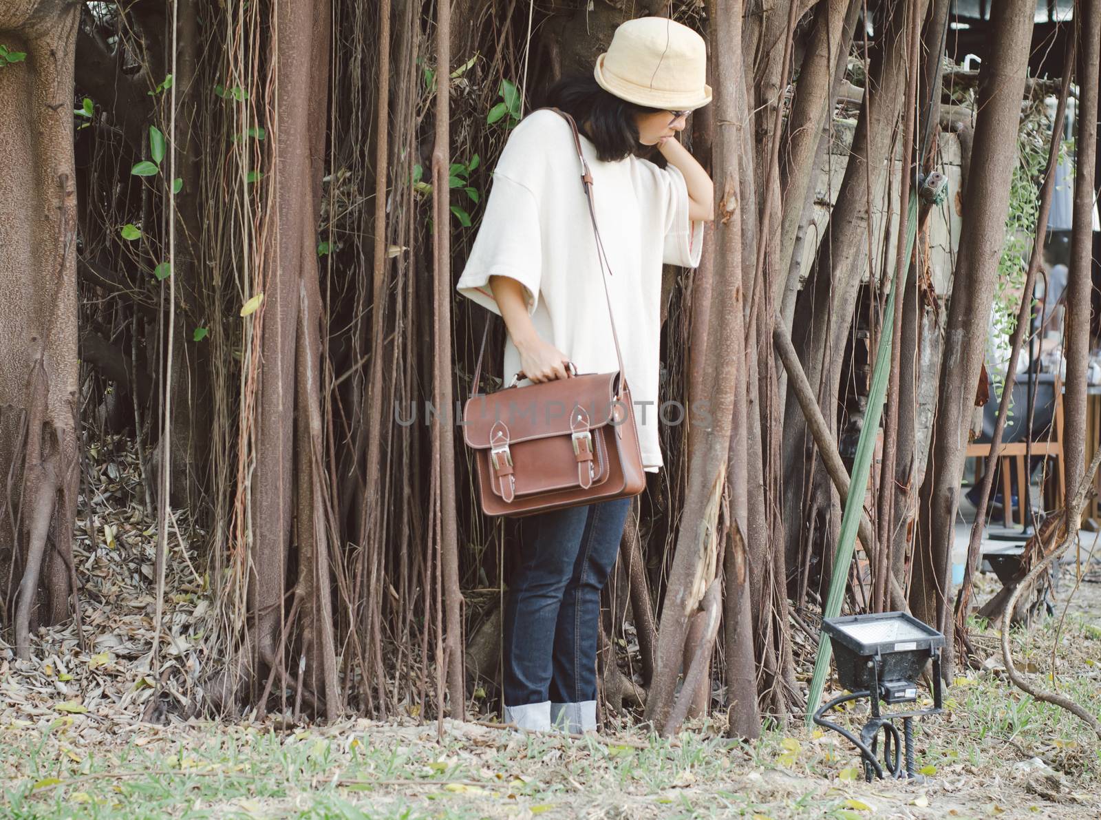 Fashion woman with vintage leather bag on nature background, retro filter