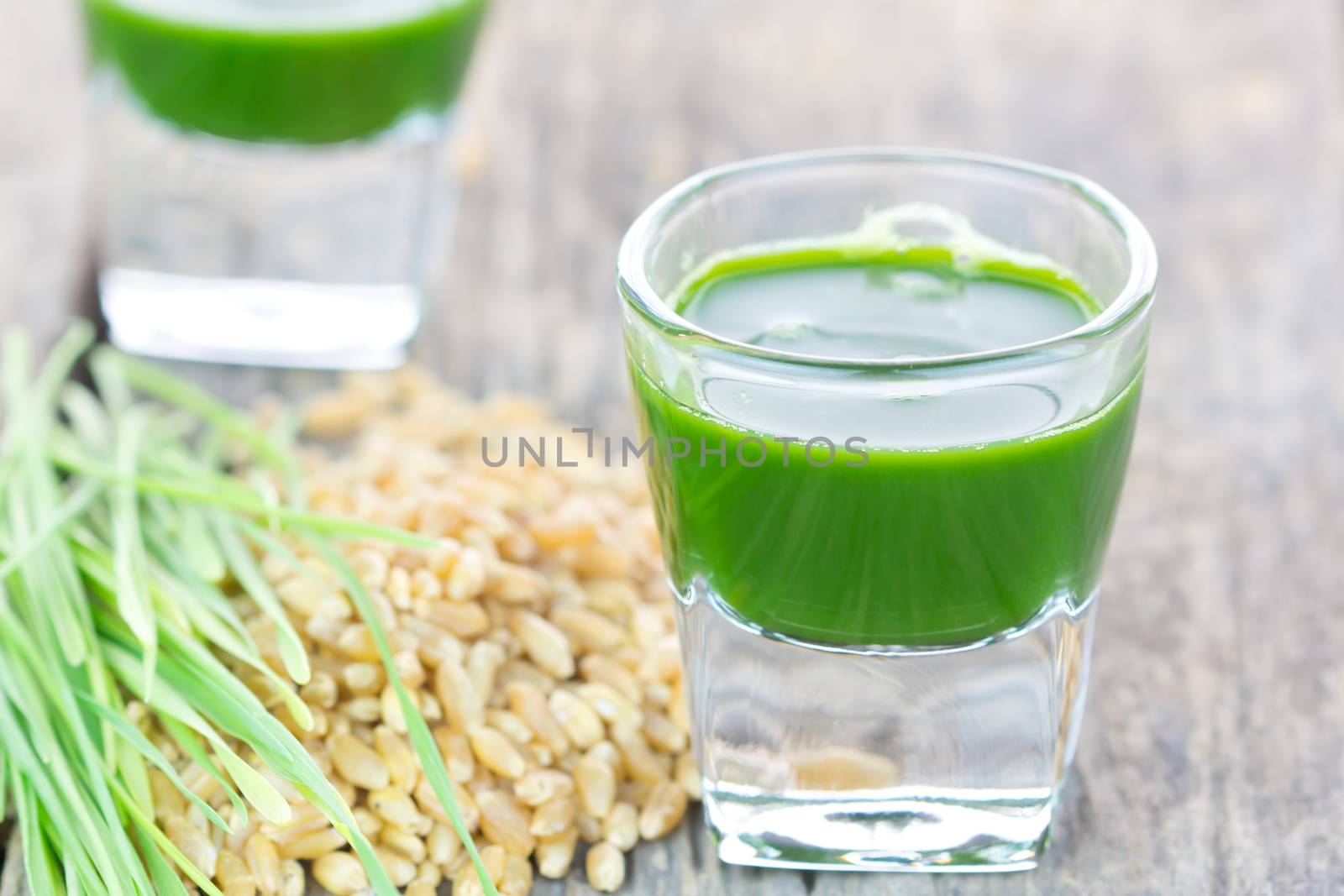 Wheat grass juice with fresh wheat grass and wheat on white background