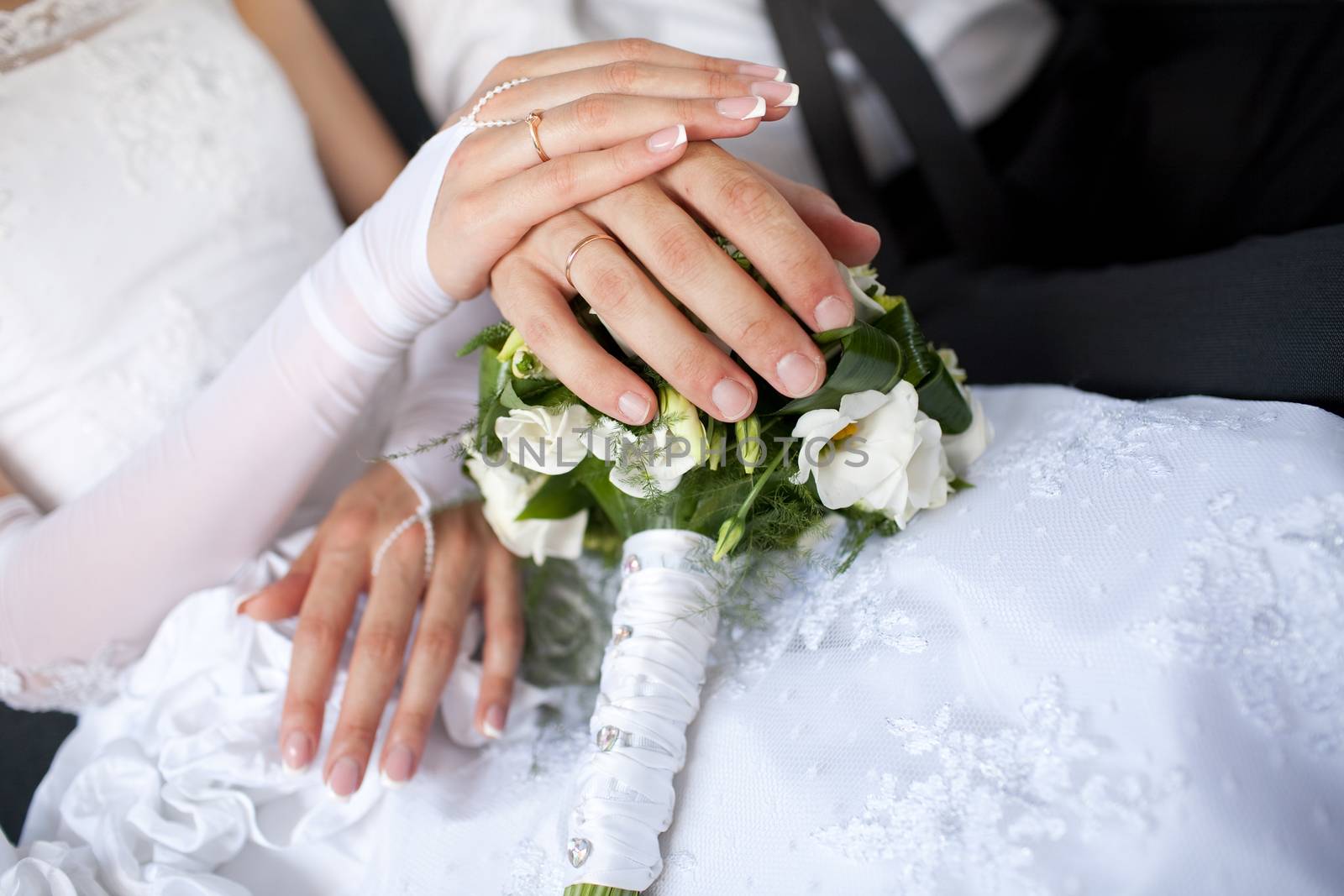 hands with wedding rings over the bouquet