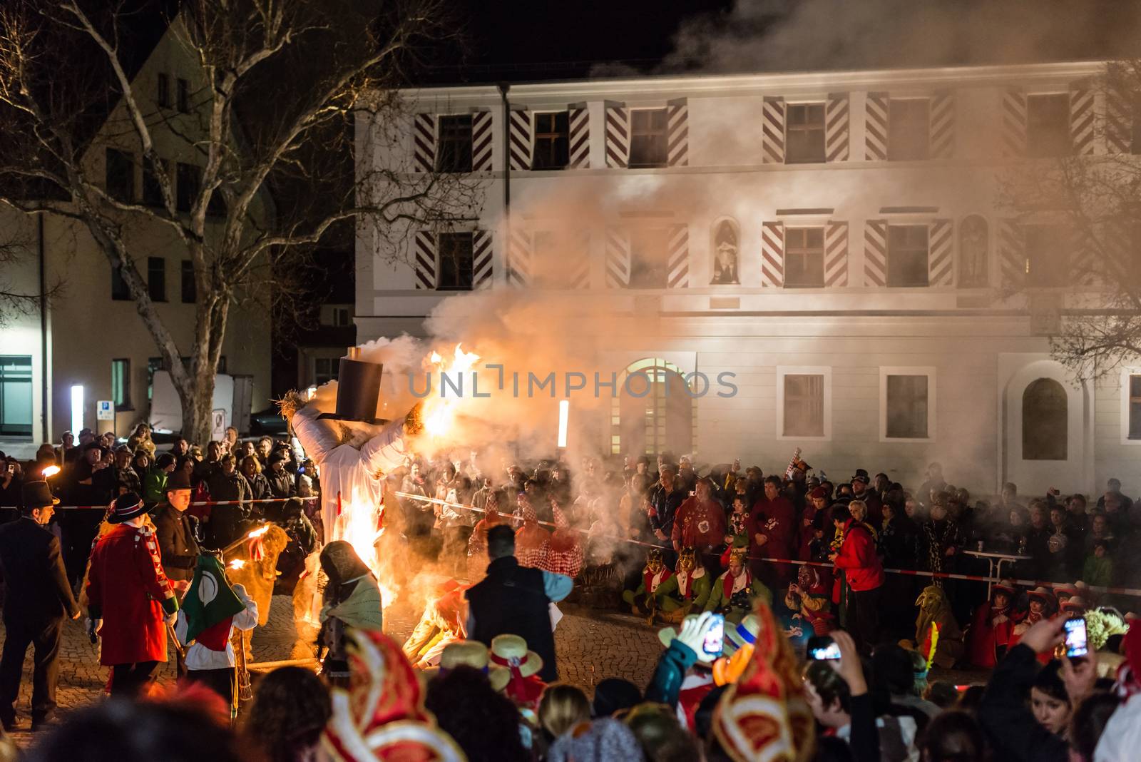 NEUHAUSEN, GERMANY ��� MARCH 4, 2014: Masked people are celebrating the end of carnival (fasnet) season by burning a puppet that is wearing a traditional costume (called the ���H��s���) symbolizing carnival on March 4, 2014 in Neuhausen (near Stuttgart), Germany. Carnival has a very long tradition in Neuhausen with influences of the swabian alemanisch culture that can be seen by the wooden masks people are wearing as part of their costumes.