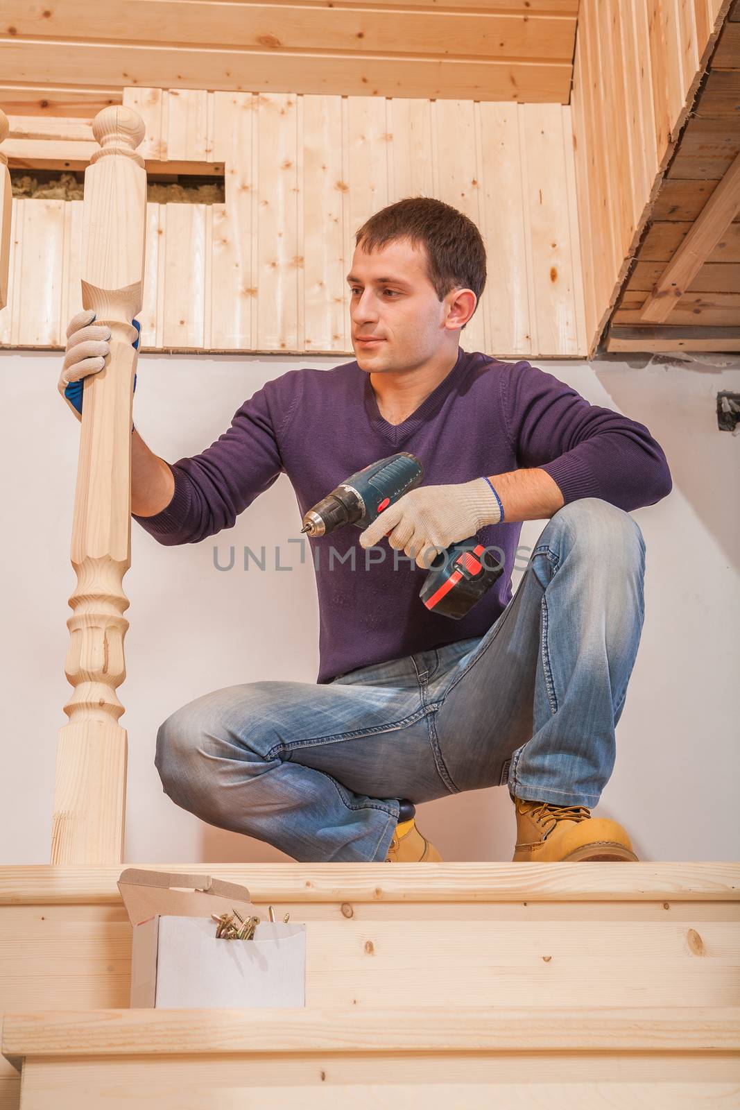 a young worker sitting and holding cordless drill by mihalec
