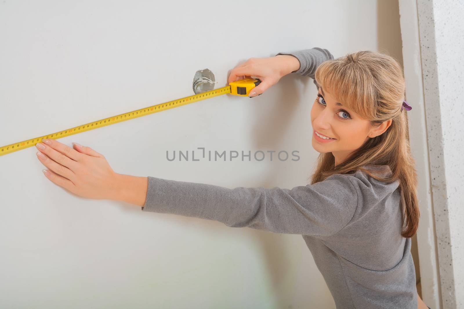 female worker measuring white wall