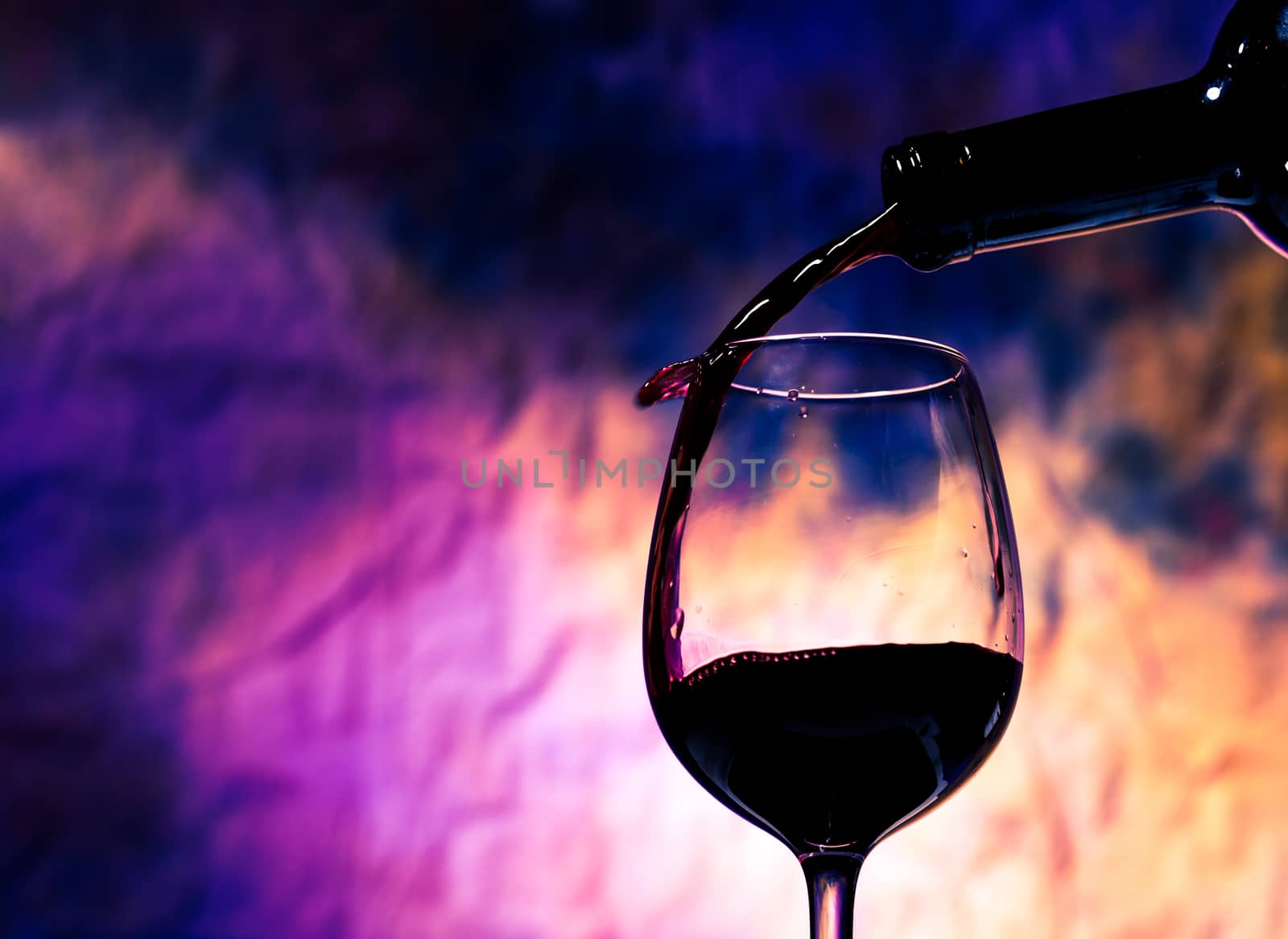 Red Wine Poured into Wineglass on background grunge bright multicolored
