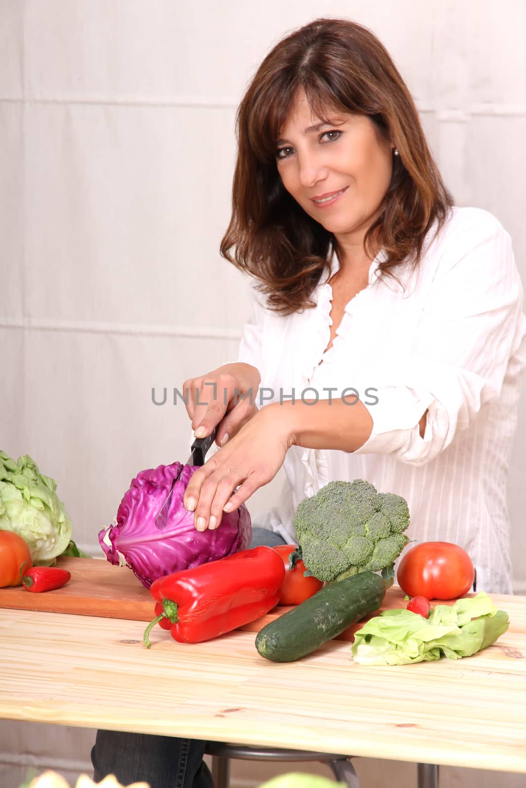 A beautiful mature woman cutting vegetables in the kitchen.