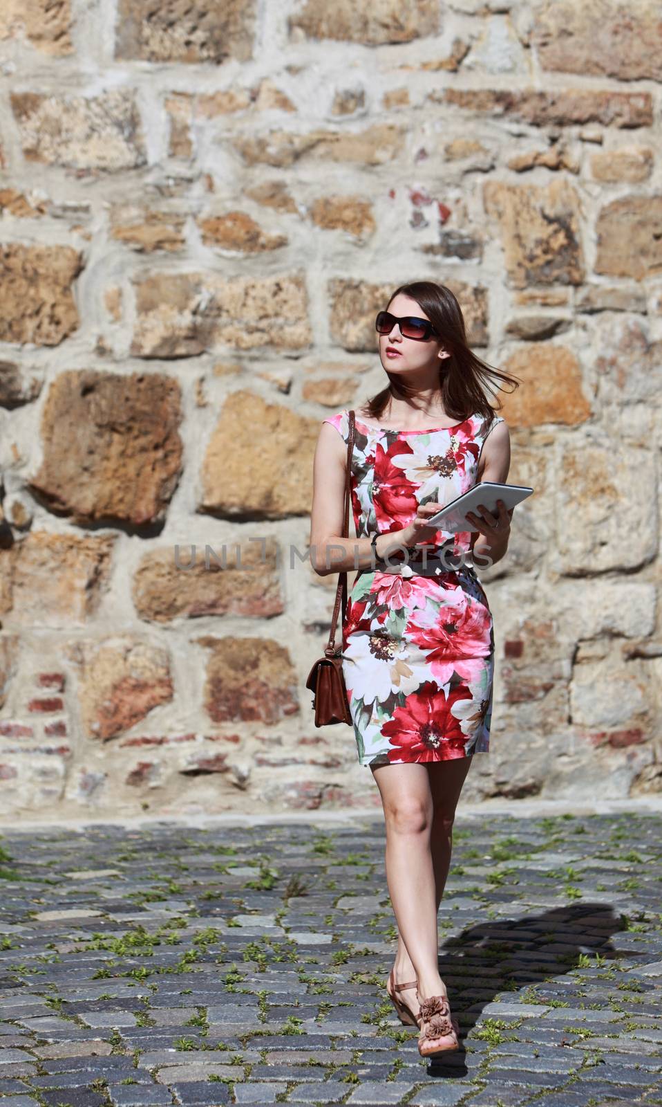 Young woman walking in the city using a map on a tablet for orientation.