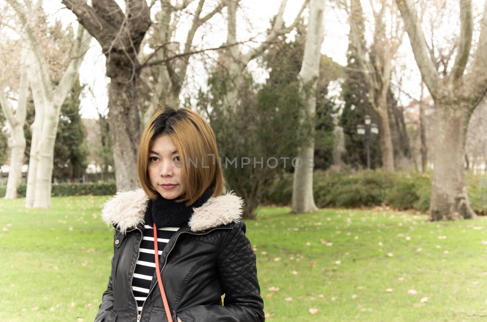 Asian woman wearing a winter coat standing in the garden.