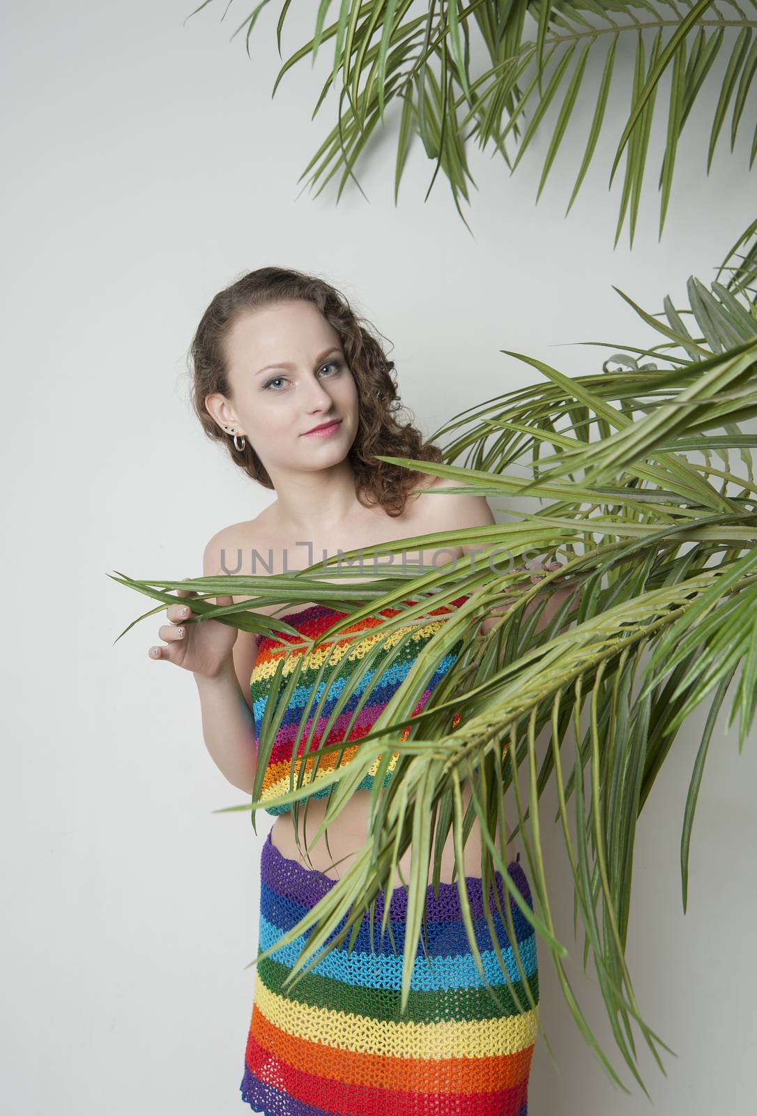 woman in a rainbow clothing under a palm tree in the Studio