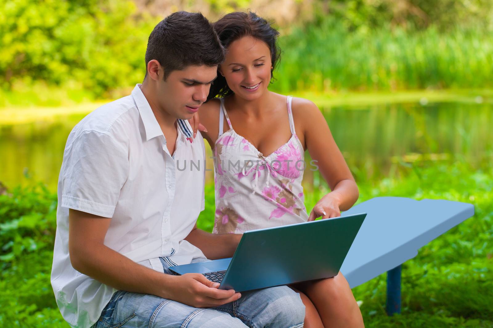 youg couple loking in laptop on nature by mihalec