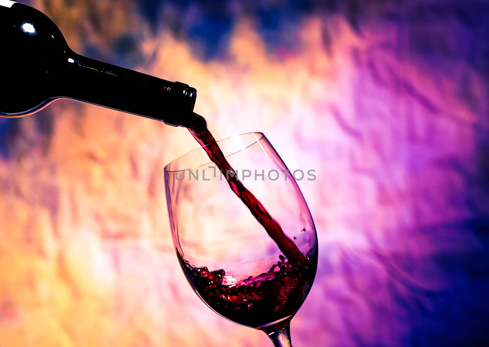 Red Wine Poured into Wineglass on background grunge bright multicolored