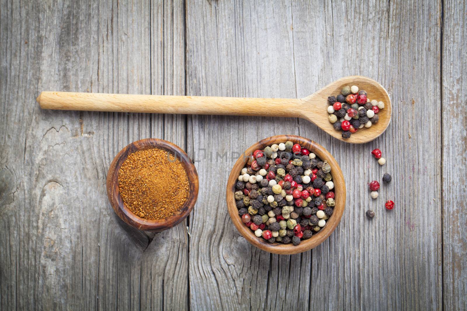 pepper spice in wooden bowl with spoon, on wooden background