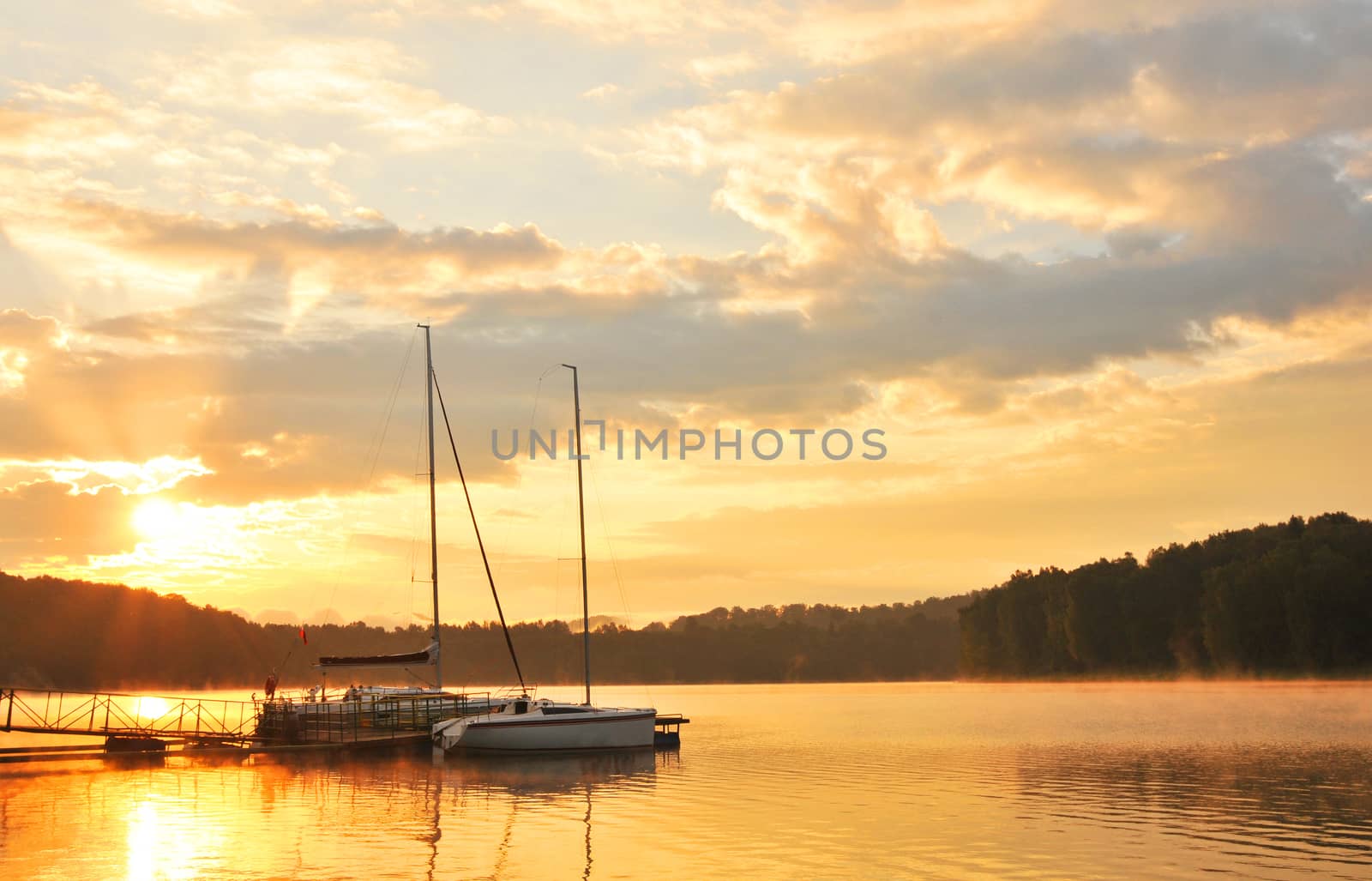 Summer landscape - sunset over lake with boats