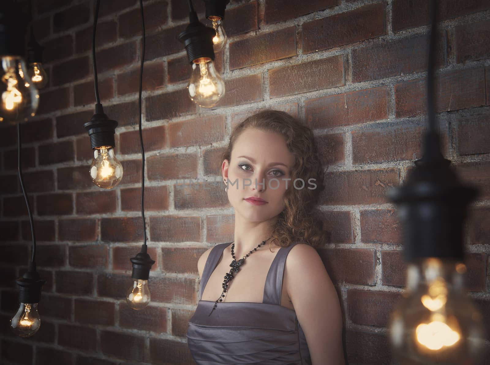 woman on a background of a wall from a brick and light bulbs