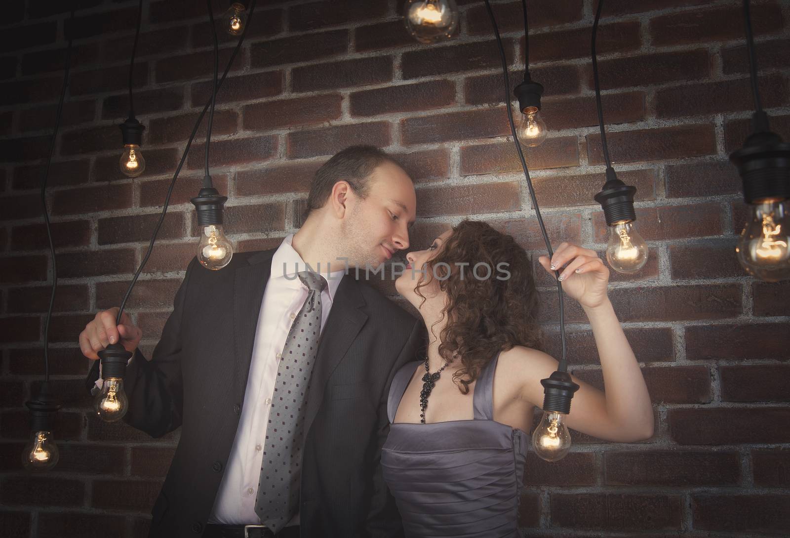 loving couple in the background of walls from a brick and light bulbs