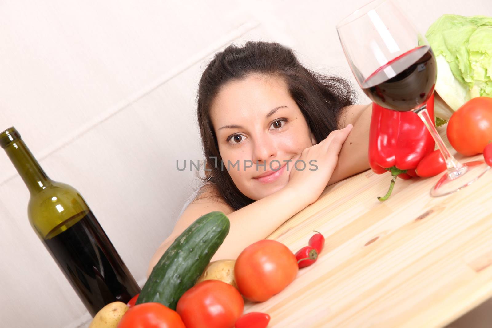 A young hispanic girl in the kitchen between vegetables.