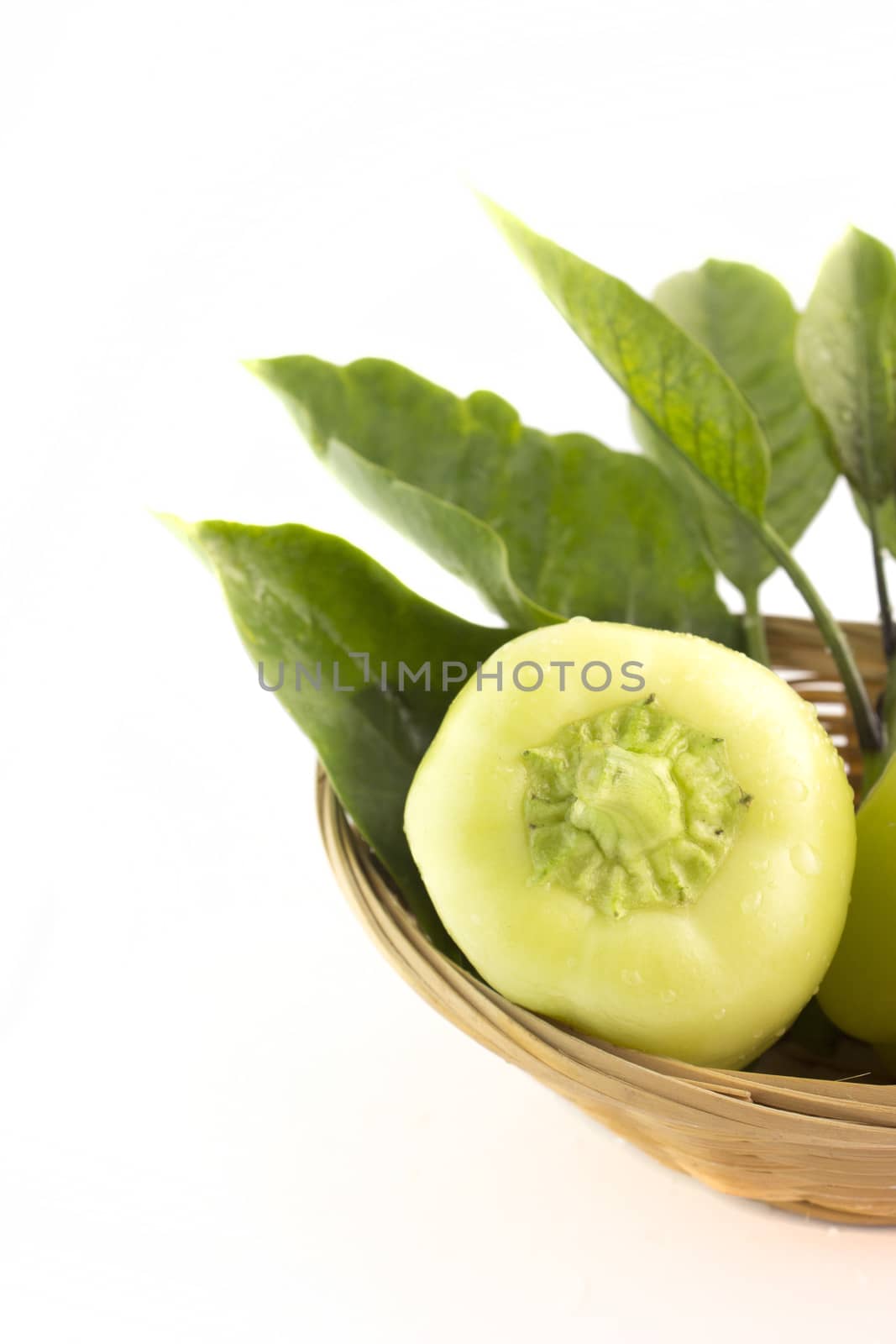 Sweet pepper with green leaves in straw Dish.