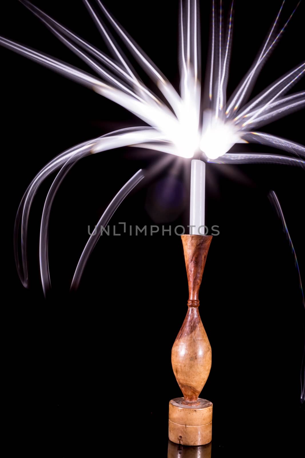 A candle in a holder glowing with bright streaks of painted light