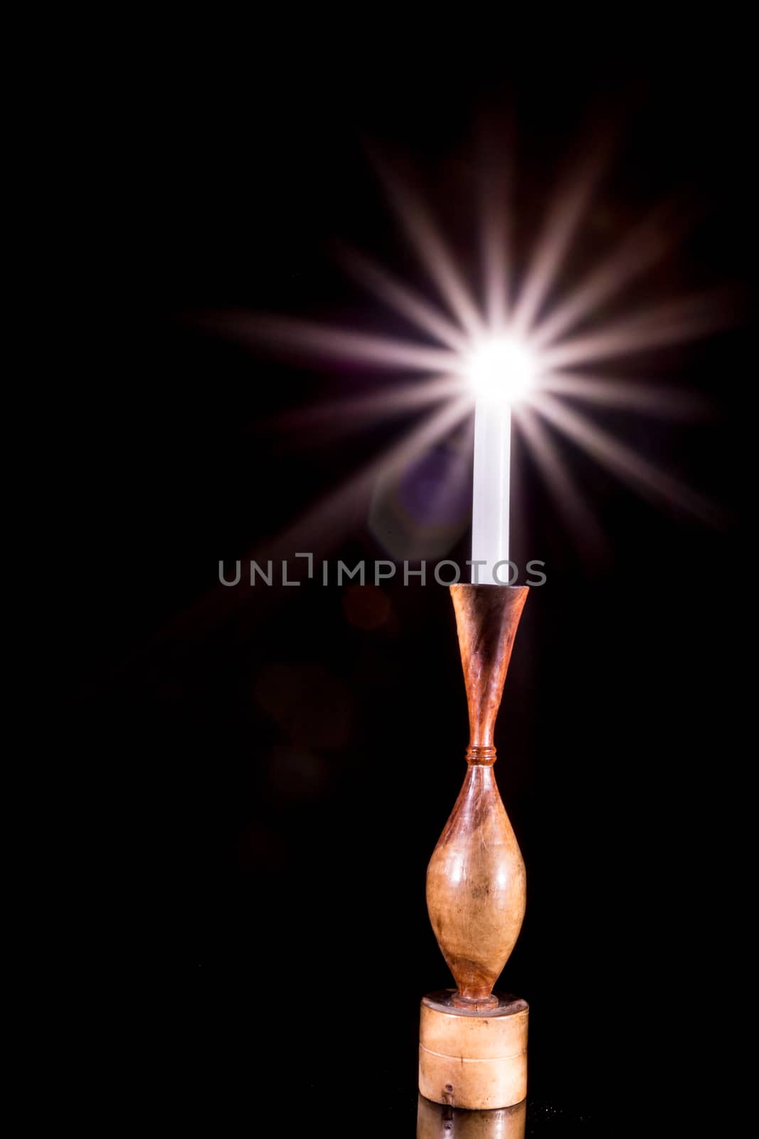 A candle in a holder glowing with bright streaks of painted light