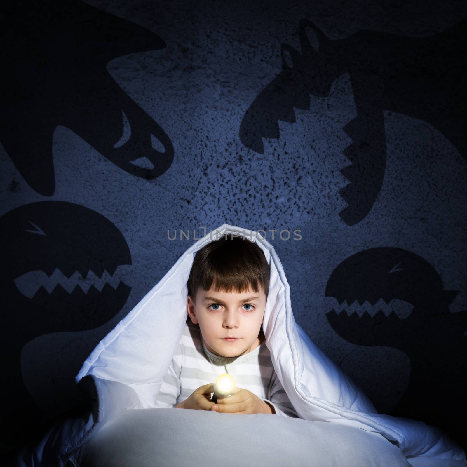 image of a boy under the covers with a flashlight the night afraid of ghosts