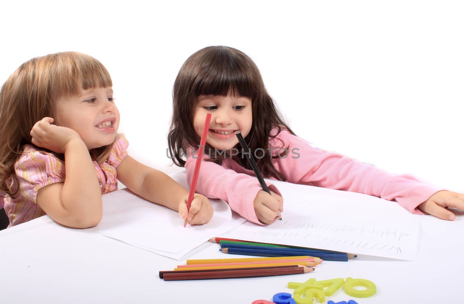 Two little preschool girls drawing with colorful pencil crayons