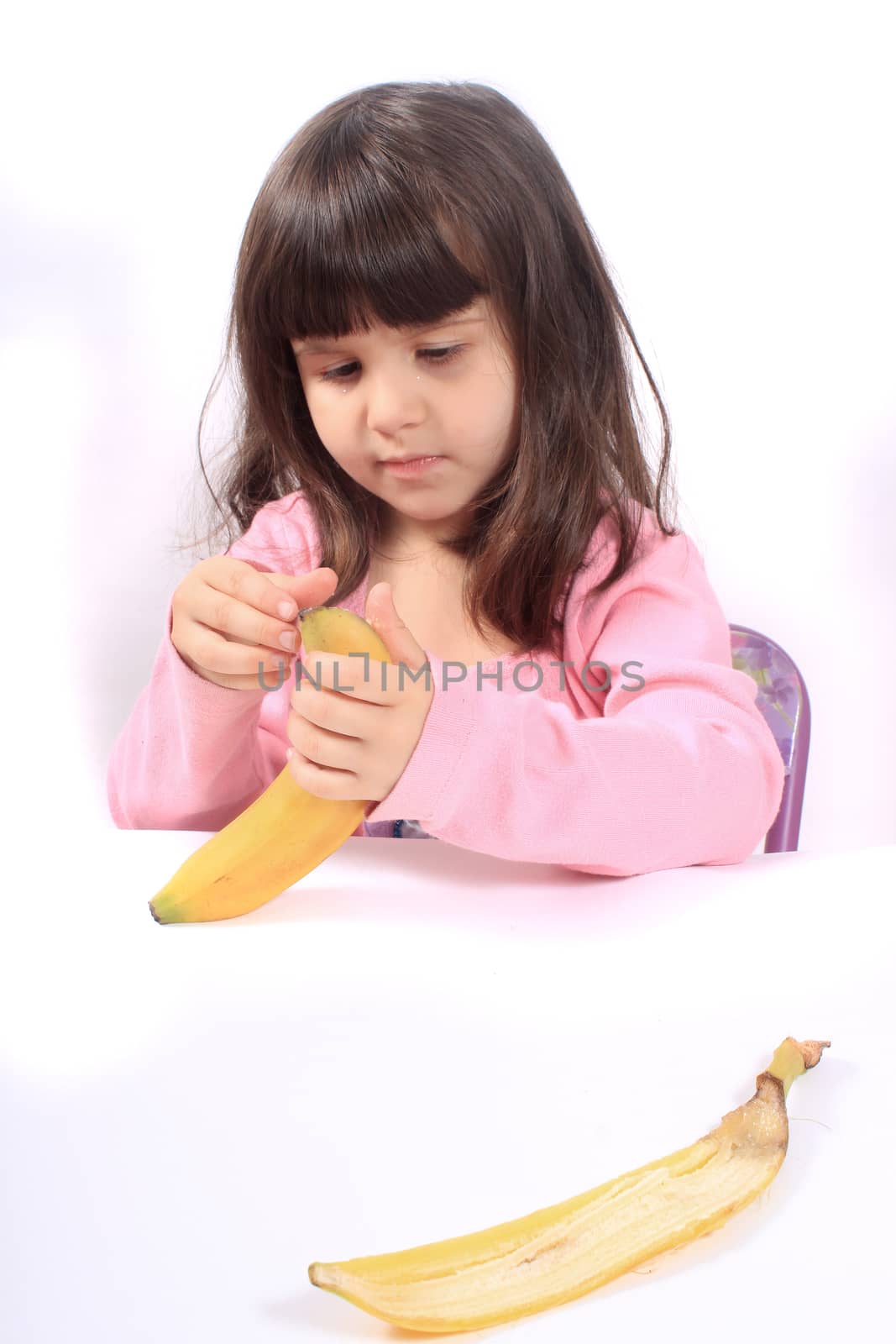 Young little girl pealing a healthy banana