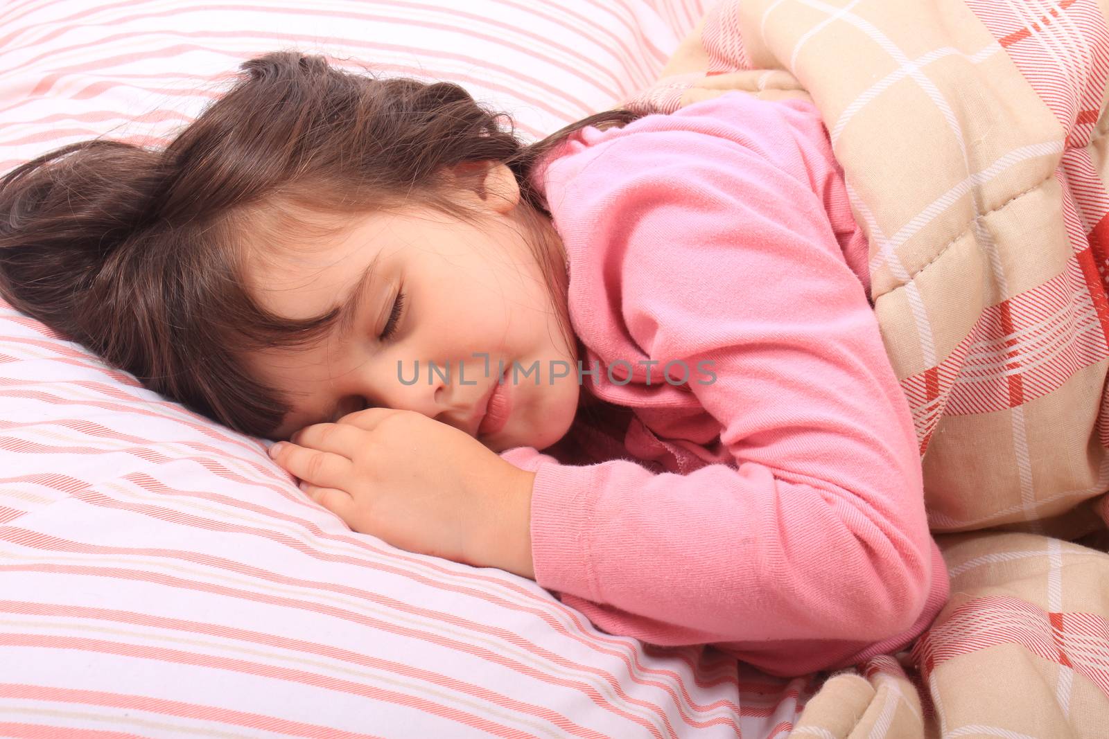 Cute little girl laying in bed sleeping cozy on her pillow and in her blanket 