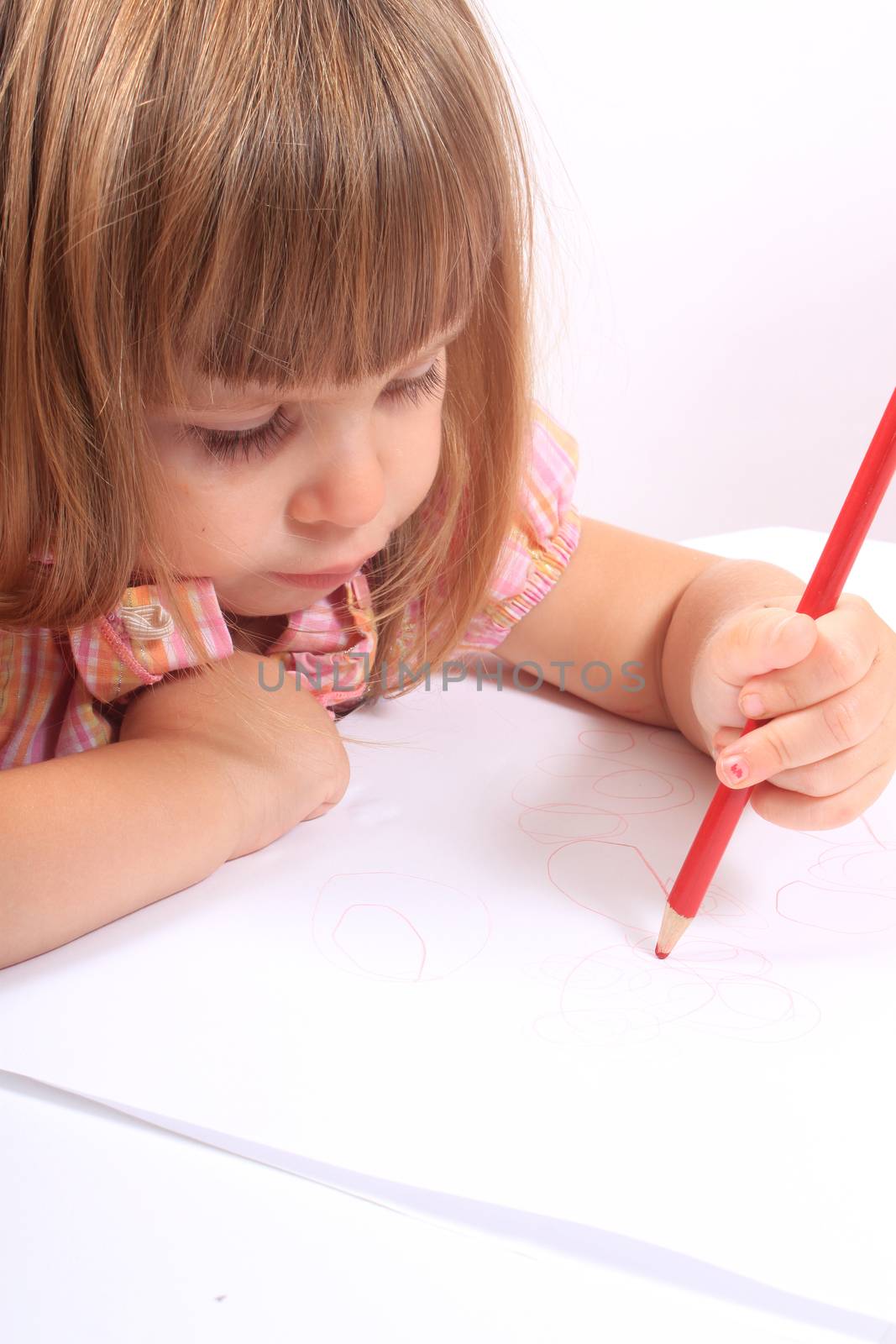 Cute little two year old girl draws pictures on white paper