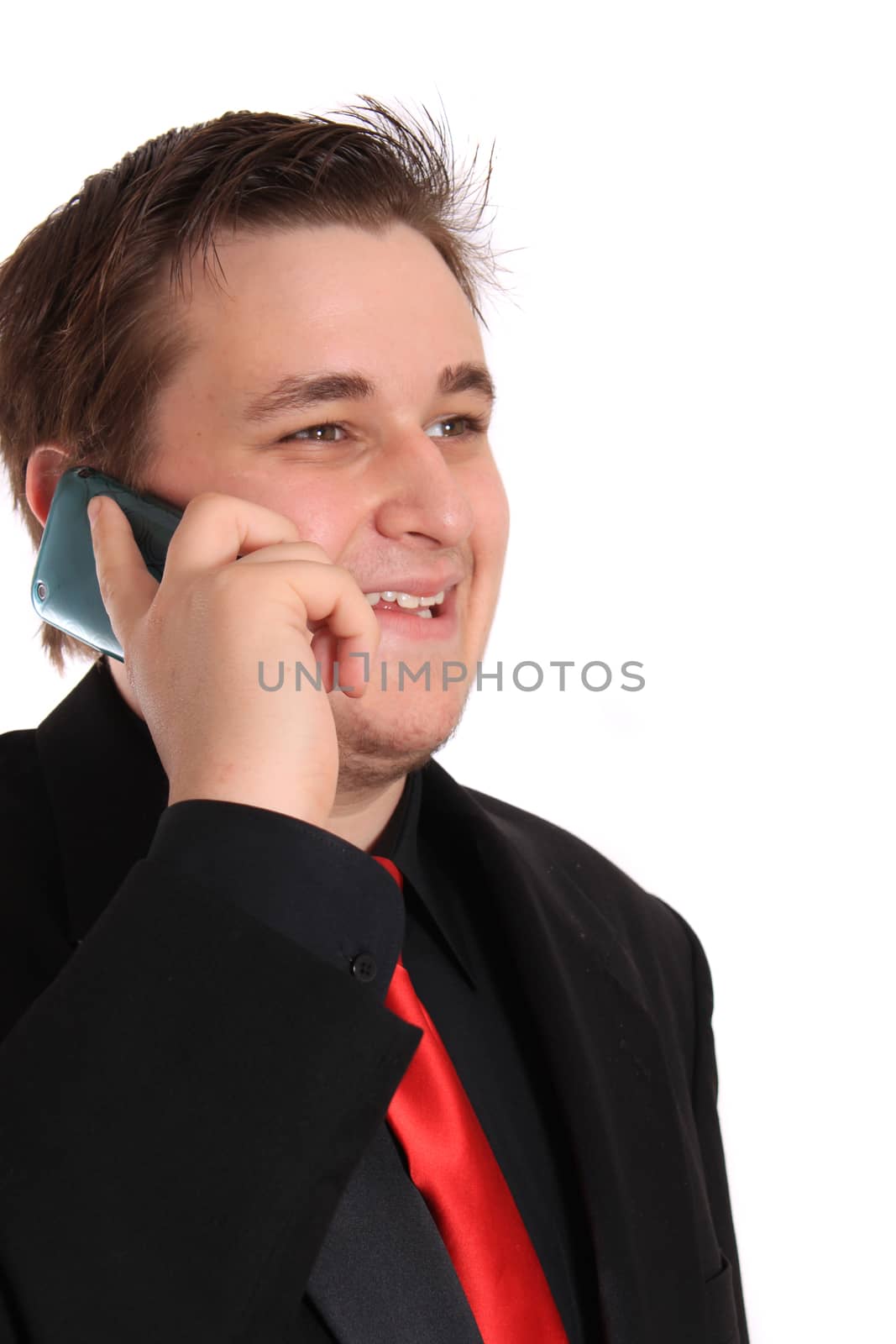 Handsome young businessman in black formal suit with red tie talking and smiling on cellphone