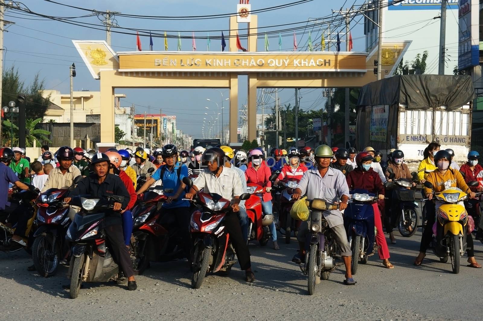 LONG AN, VIET NAM- NOV 11: Crowd of people wear helmet, ride motorbike waiting traffice signal to go to work at morning in Long An, VietNam on Nov 11, 2013