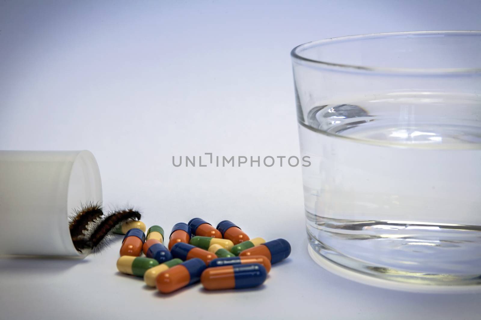 worm going out of packing medicines, Glass of water and pills isolated on white background