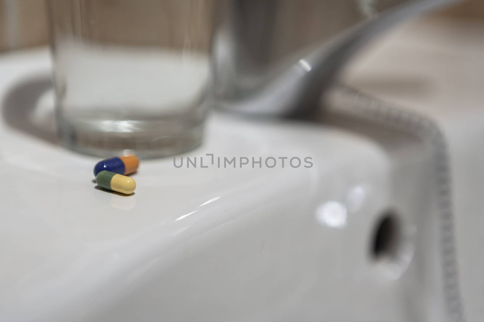 Glass of water and pile of blister packs in bathroom shelf