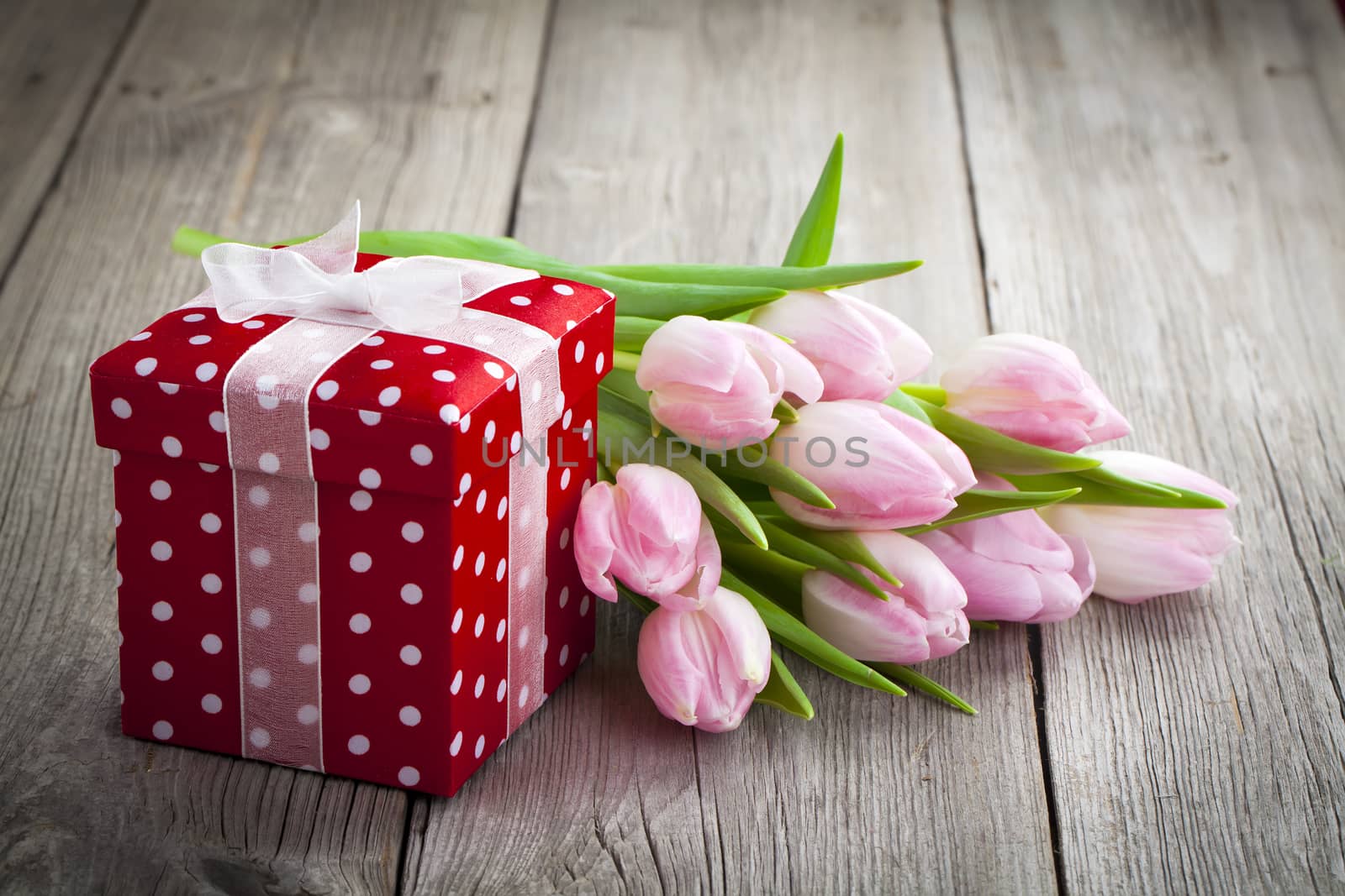 beautiful tulips with red polka-dot gift box. happy mothers day, romantic still life, fresh flowers. on wooden background