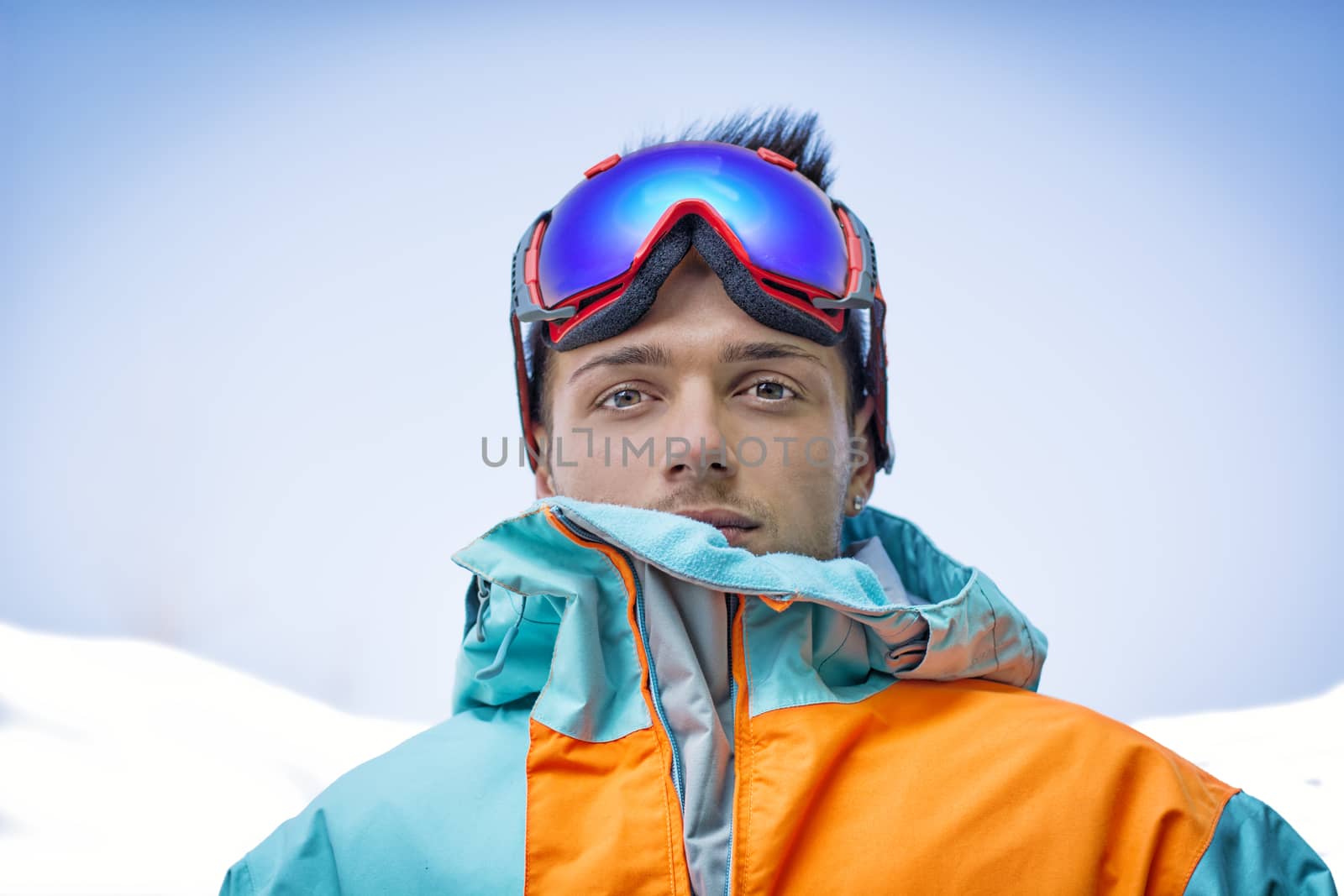 Friendly attractive skier or snowboarder against blue sky looking at camera