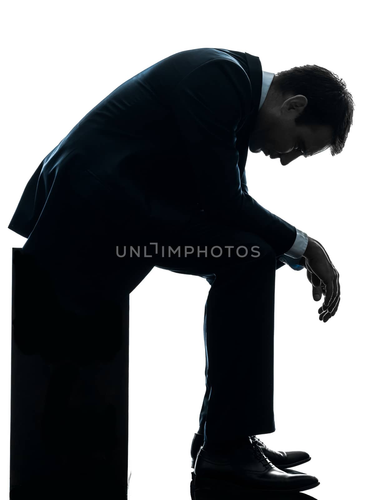 one caucasian sad business man sitting pensive looking down in silhouette studio isolated on white background