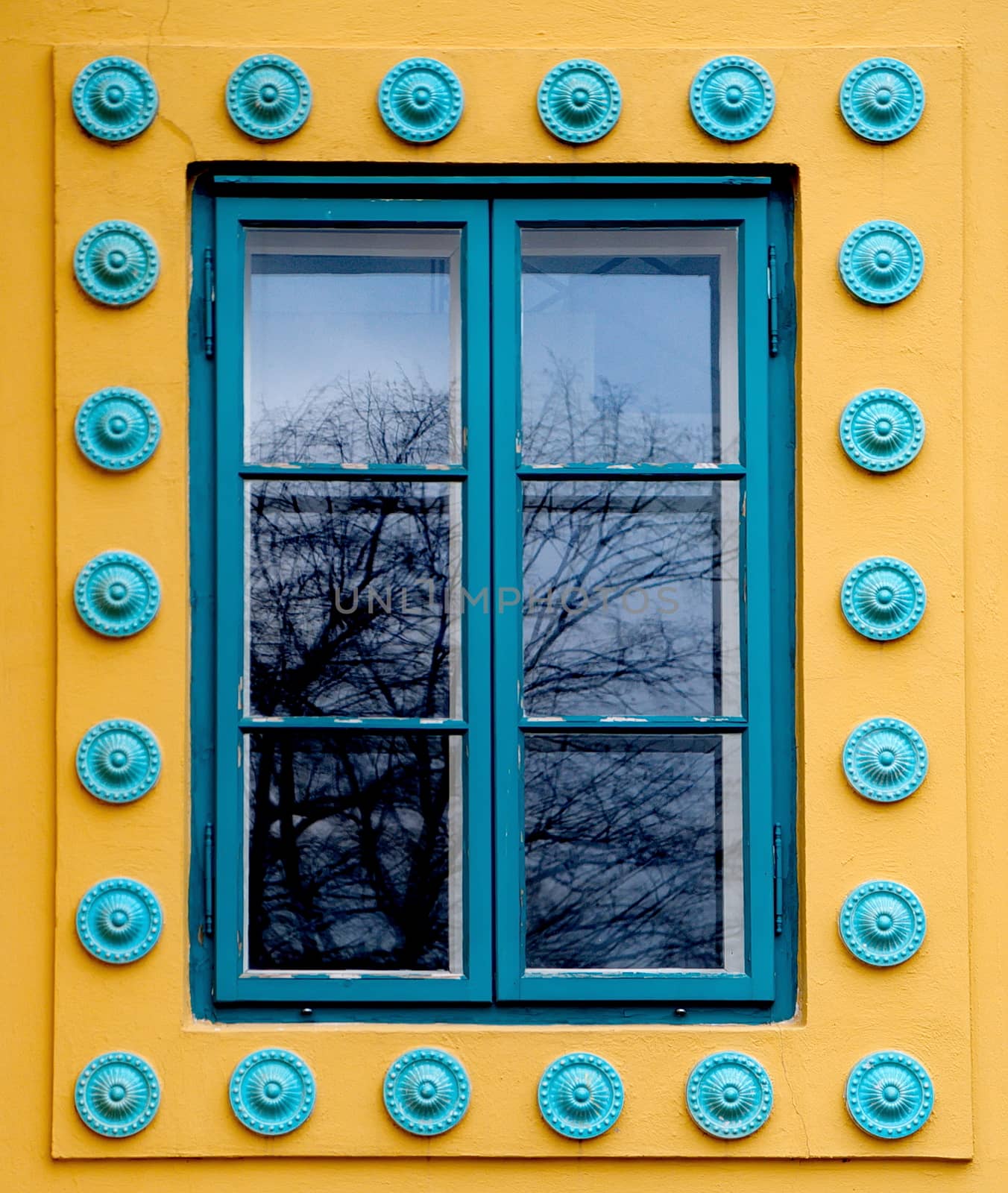 Cyan colored window on a yellow wall