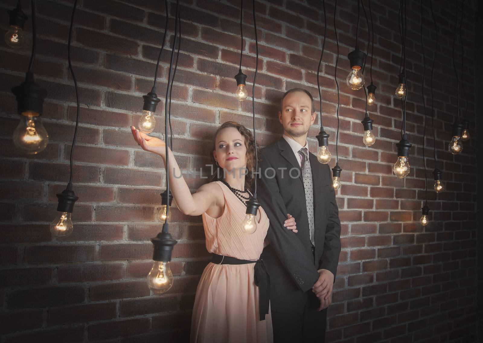 loving couple in the background of walls from a brick and light bulbs