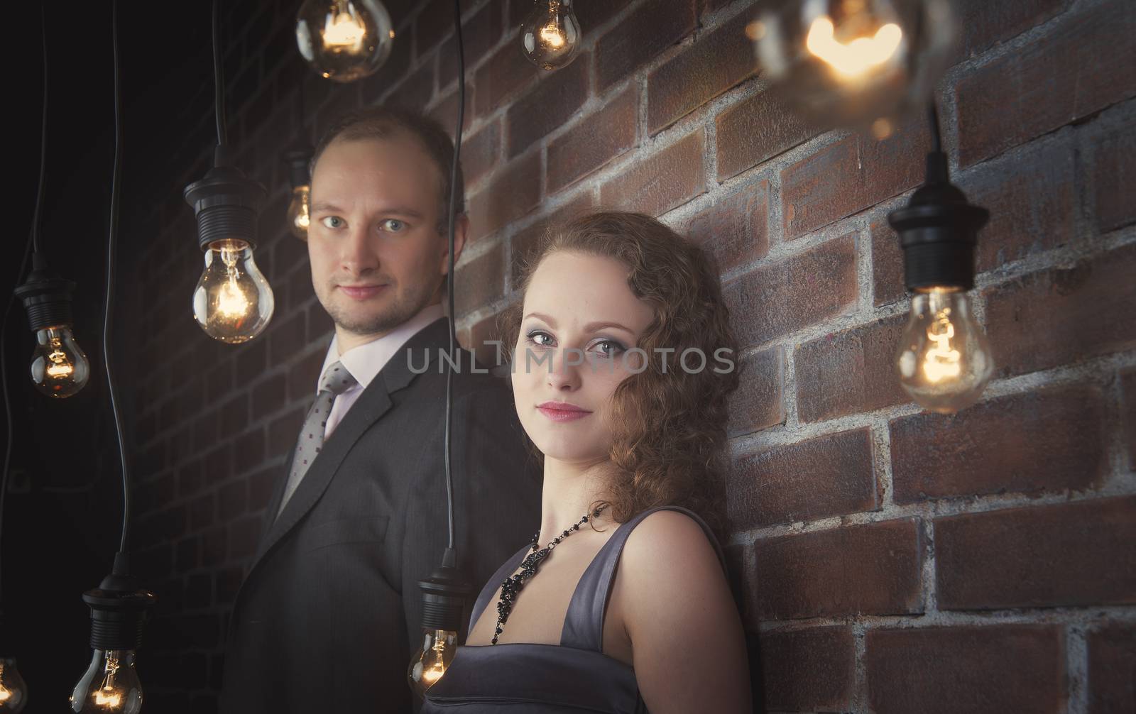 loving couple in the background of walls from a brick and light bulbs