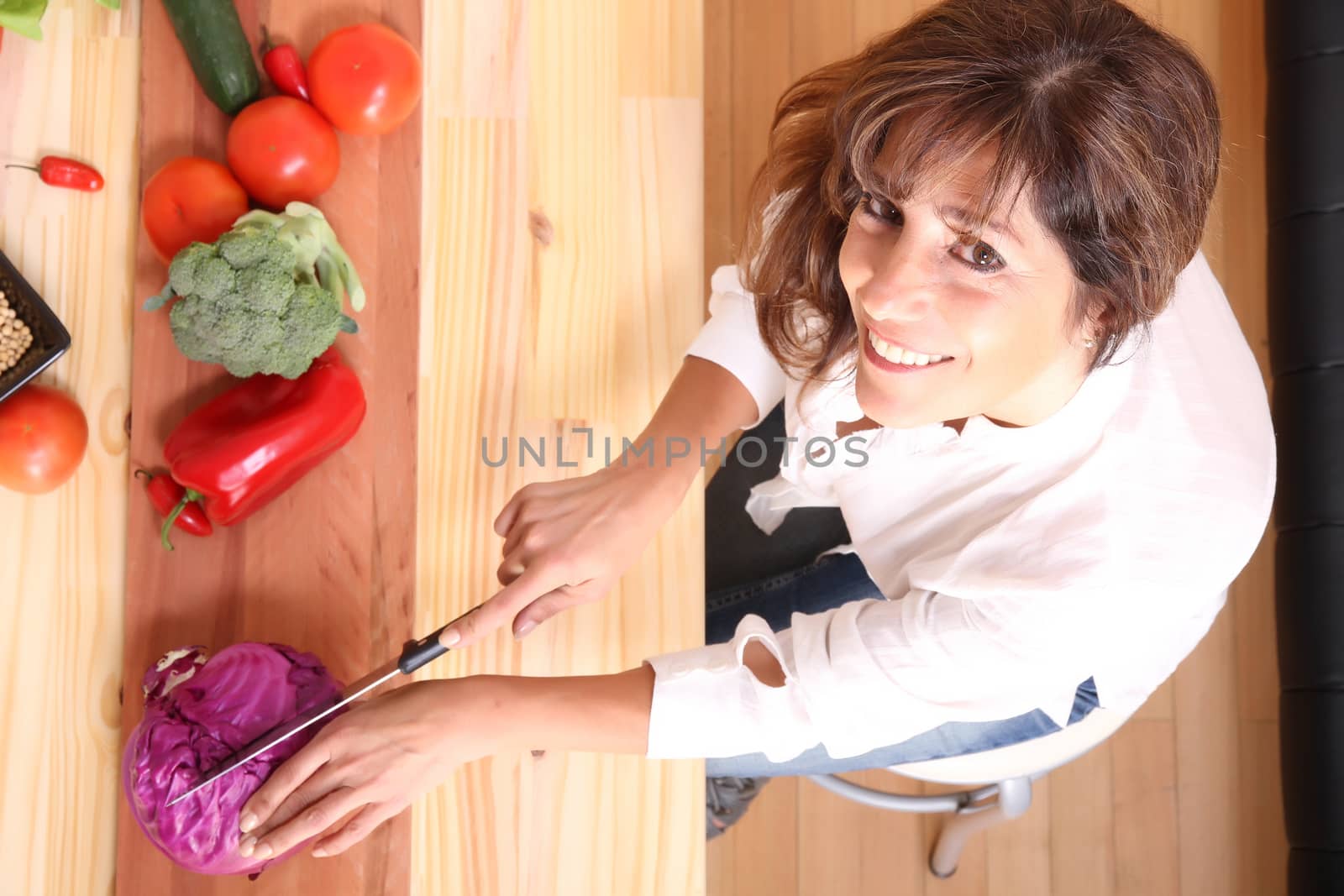 A beautiful mature woman cutting vegetables in the kitchen.