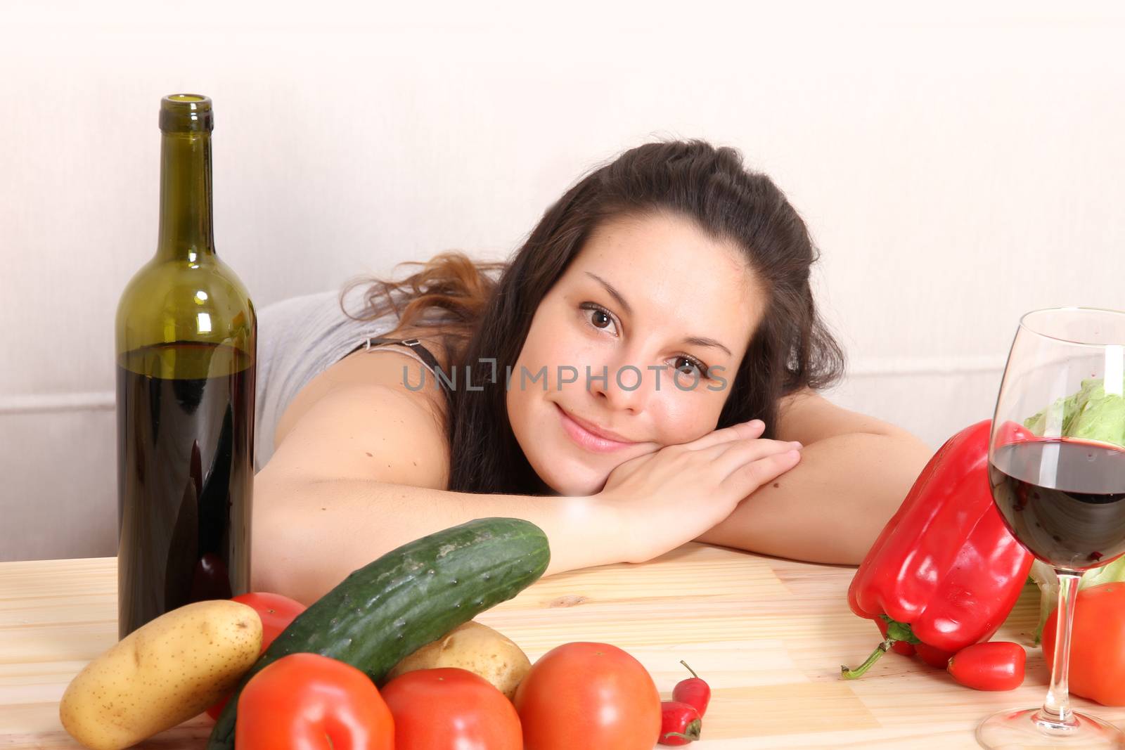 A young hispanic girl in the kitchen between vegetables.