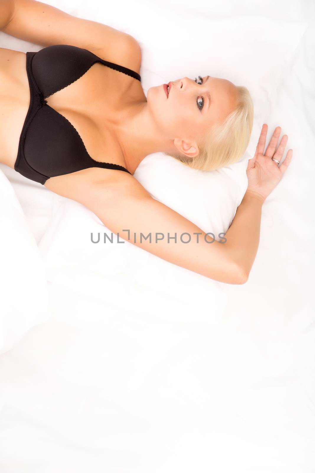 A young blonde woman laying in bed.