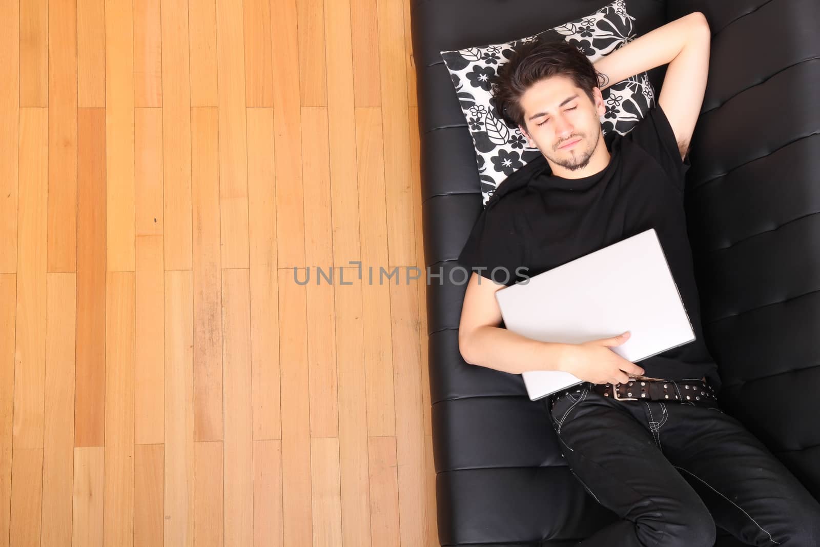 A young hispanic man with a laptop on the Sofa.