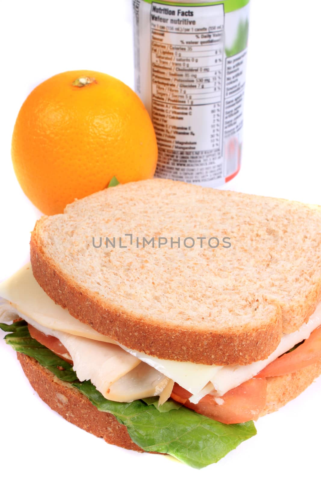 Turkey and cheese sandwich on whole wheat bread with tomato and lettuce inside a zipped bag ready for lunch and orange on the side