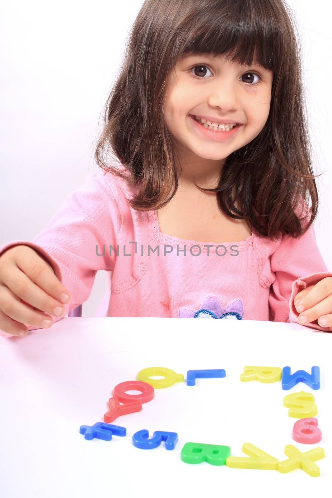 Young little preschool girl with funny expression playing with letters and numbers