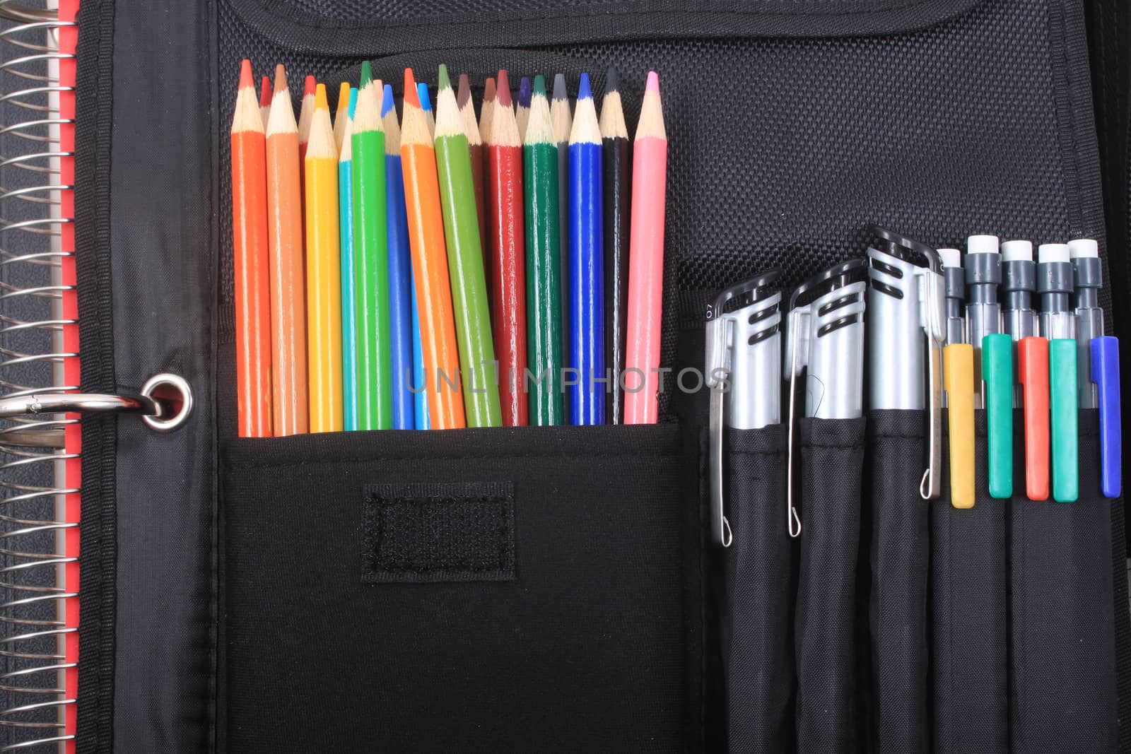 Colorful sharpened  pencil crayons for school in three ring binder pocket with pens on the side