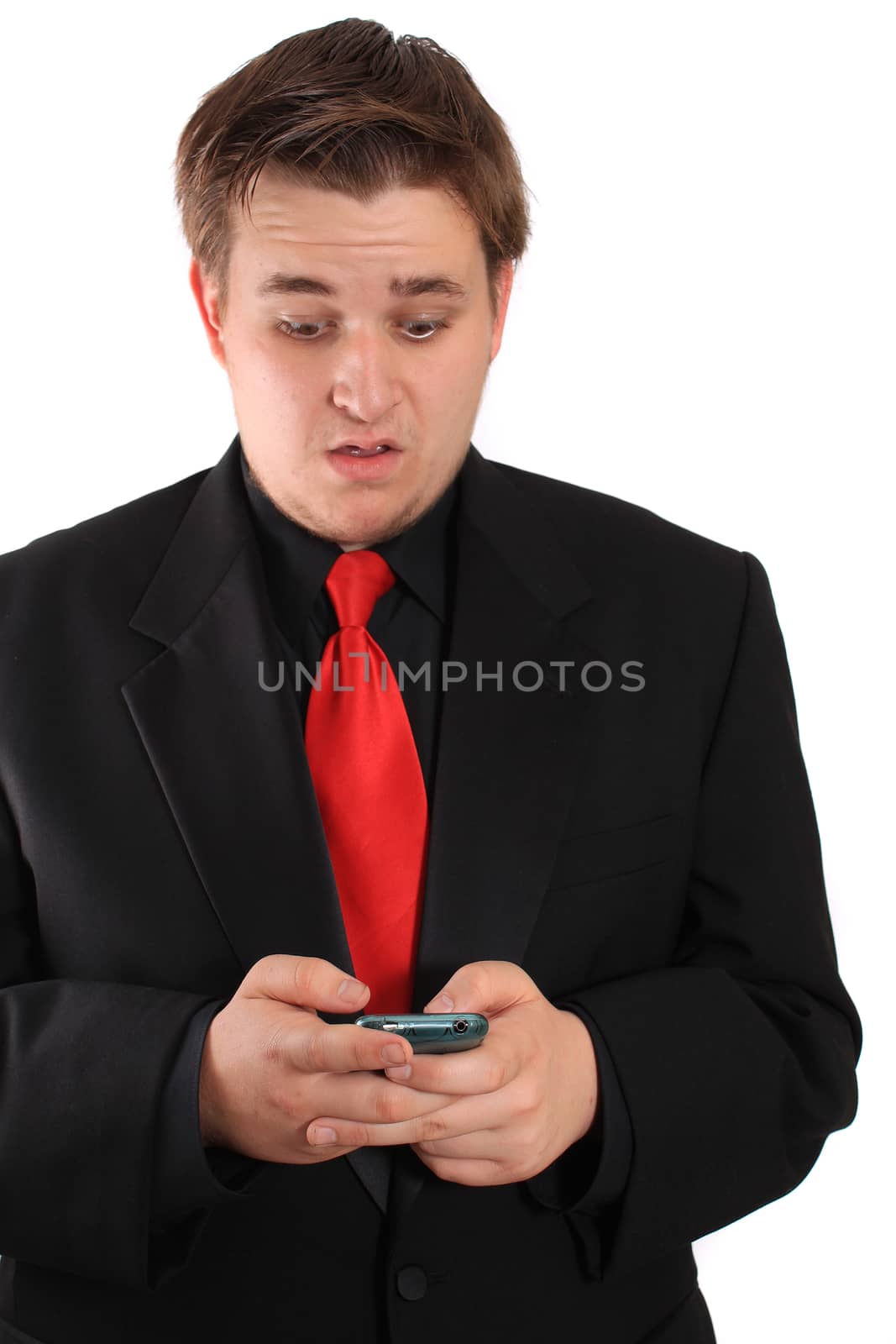 Handsome young businessman in black formal suit with red tie reacting to reading a text message on  cellphone