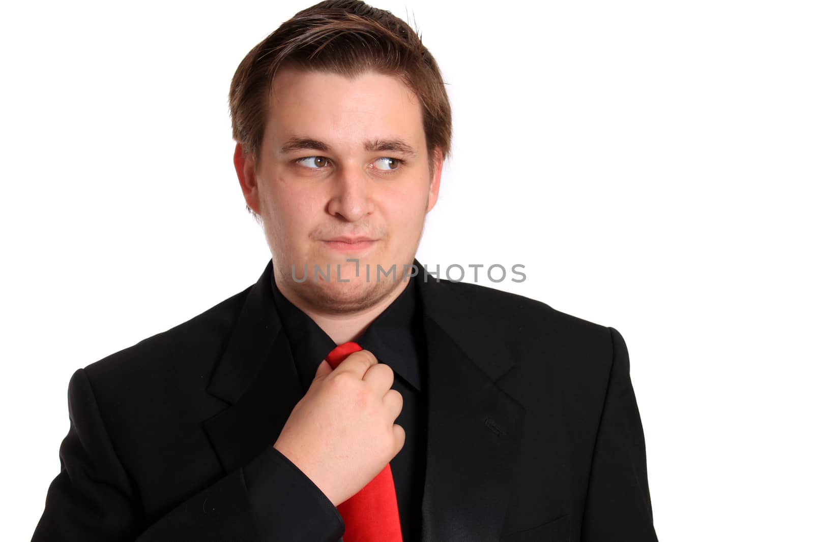 Handsome young businessman loosening or fixing his red tie on a white background