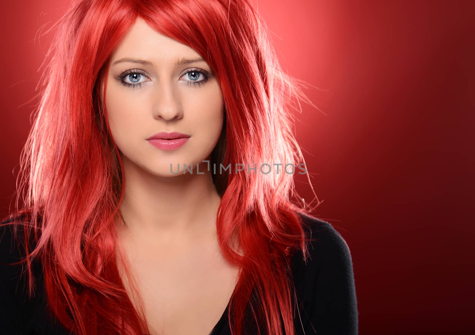 Beautiful red haired woman posing over red background