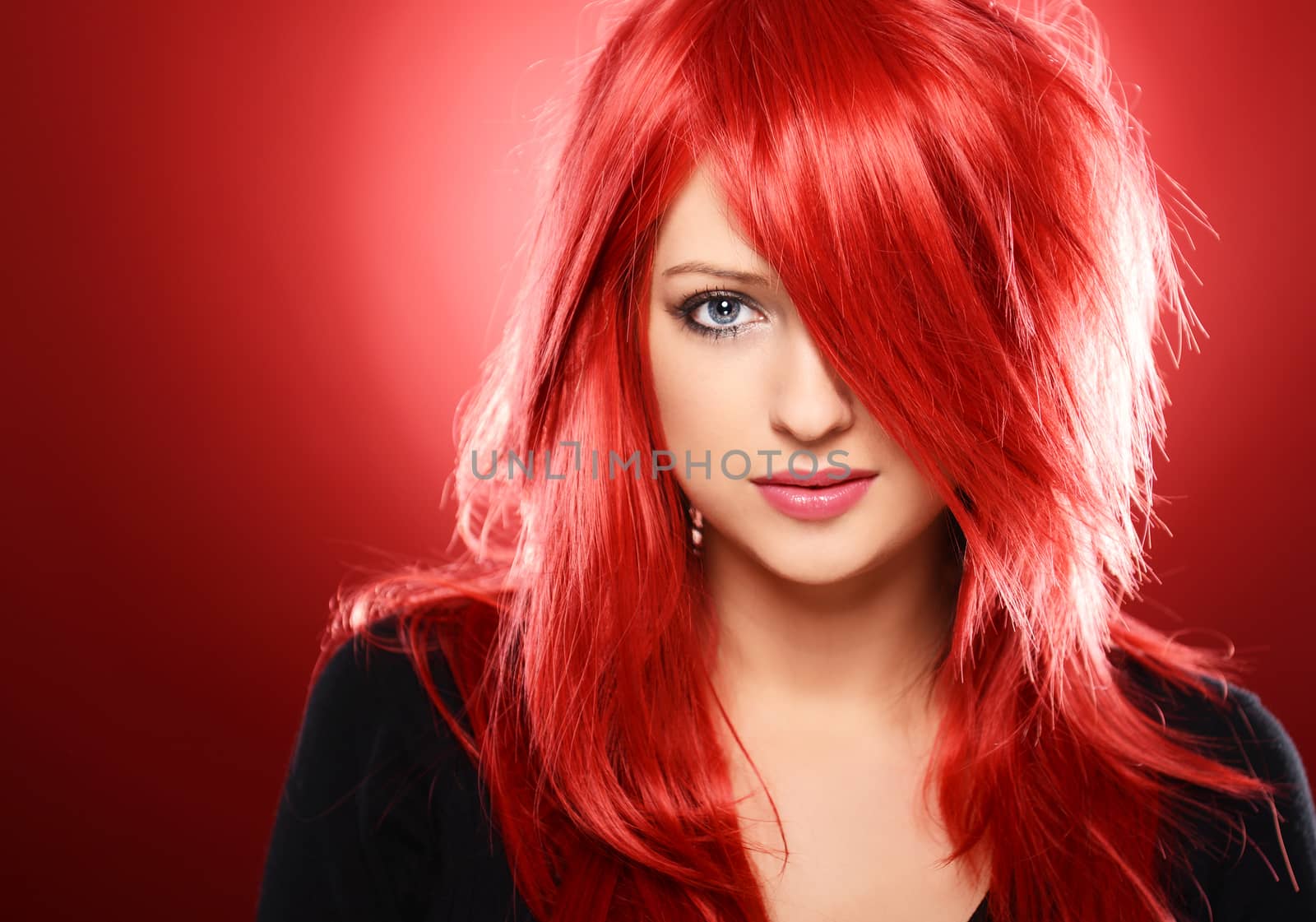 Beautiful red haired woman posing over red background